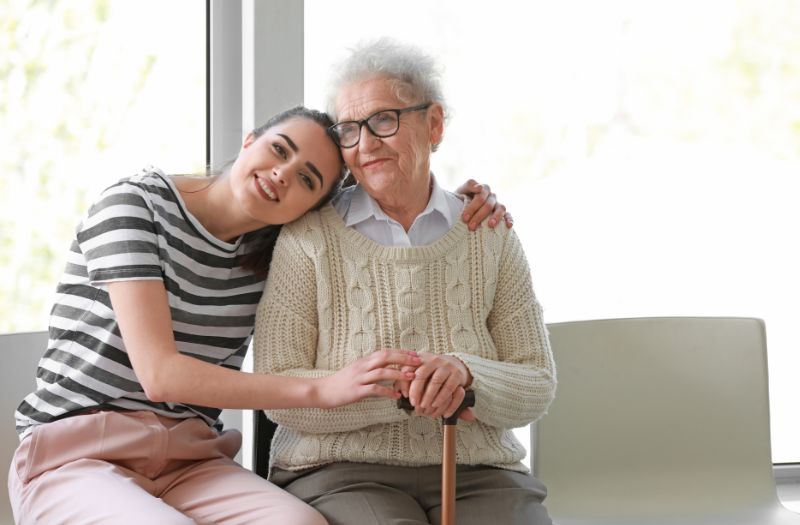 Compassionate caregiver providing personalized 24-hour elder care to a senior resident inside a sunlit Kennewick residential home.